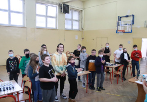 Uczestnicy konkursu szachowego stoją w grupie czekając na ogłoszenie wyników konkursu.