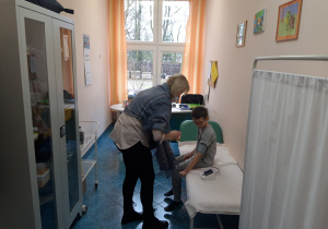 Pielęgniarka mierzy ciśnienie dziecku w szkolnym gabinecie.