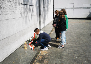 Uczniowie składają wieniec przy pomniku upamiętniającym ofiary Holocaustu.