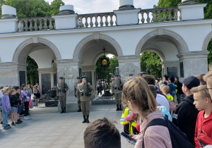 Grupa ludzi obserwuje uroczystą zmianę warty przy Grobie Nieznanego Żołnierza na placu Piłsudzkiego w Warszawie.