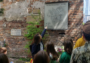 Przewodnik prezentuje uczestnikom wycieczki pozostały fragment murów Getta Warszawskie.