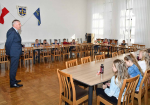 Uczniowie przy stołach w sali konferencyjnej, słuchają Pana Burmistrza.