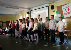 Klasa trzecia śpiewa piosenkę dla nauczycieli podczas przedstawienia z okazji Dnia Edukacji Narodowej.