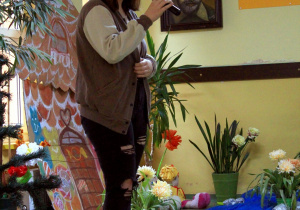 Uczennica śpiewa do mikrofonu piosenkę z bajki. W tle bajkowa dekoracja.