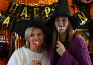 Nauczycielki w kapeluszach czarownic na tle napisu Happy Halloween.