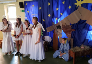 Cztery uczennice z klasy szóstej przebrane za anioły śpiewają kolędę.