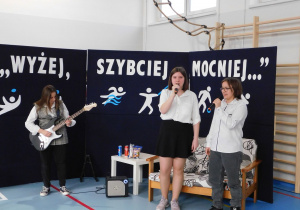 Uczennice śpiewają popularną piosnkę do akompaniamentu gitary elektrycznej.