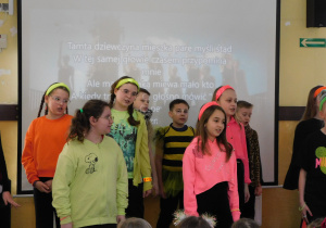 Uczniowie śpiewają na scenie piosenkę.