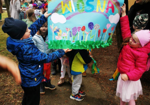 Uczniowie grupy przedszkolnej prezentują plakat na powitanie wiosny.