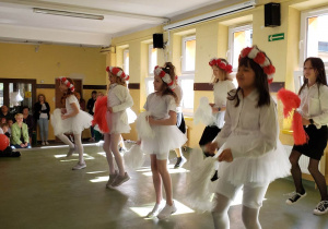 Uczennice prezentują taniec w strojach biało czerwonych podczas apelu z okazji 3 Maja.