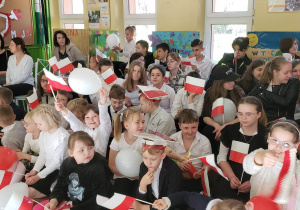 Społeczność szkolna na widowni w biało- czerwonych strojach.