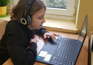 Uczennica przy komputerze rozwiązuje zadania konkursowe.