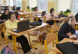 Uczniowie przy komputerach rozwiązują zadania konkursowe.