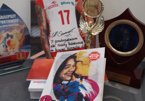 Zdjęcie z autografem polskiej siatkarki Malwiny Smarzek oraz jej trofea sportowe.