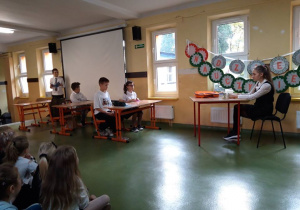 Uczniowie grają scenę przedstawiającą lekcję w klasie.