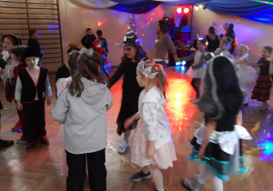 Dzieci tańczą podczas szkolnego balu choinkowego.