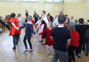 Organizatorzy spotkania w śląskich strojach ludowych tańczą z uczniami.
