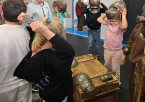 Dzieci oglądają i przymierzają rekwizyty historyczne.