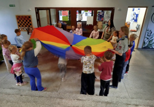 Dzieci uczestniczą w zabawie z kolorową chustą.