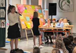 Uczniowie prezentują program artystyczny z okazji Dnia Edukacji Narodowej, występując przed zgromadzoną publicznością.
