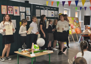 Uczniowie prezentują dyplomy przed zgromadzoną publicznością.