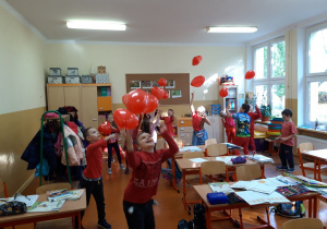 Dzień bez Przemocy. Dzieci ubrane na czerwono bawią się czerwonymi balonami.