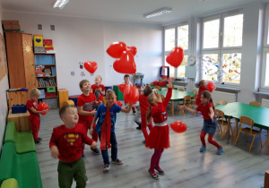 Dzień bez Przemocy. Dzieci ubrane na czerwono bawią się czerwonymi balonami.
