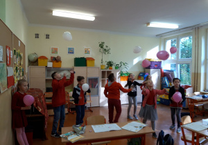Dzień bez Przemocy. Dzieci ubrane na czerwono bawią się balonami.