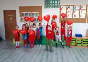 Dzień bez Przemocy. Dzieci ubrane na czerwono trzymają w dłoniach czerwone balony.