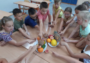 Dzieci pokazują owoce egzotyczne.