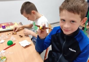 Uczeń klasy trzeciej prezentuje zbudowany przez siebie samolot z klocków.
