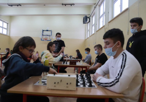 Dwóch chłopców rozgrywa partię szachową. Jeden z nich przestawia pionki na szachownicy.