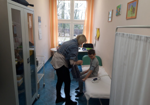 Pielęgniarka mierzy ciśnienie dziecku w szkolnym gabinecie.